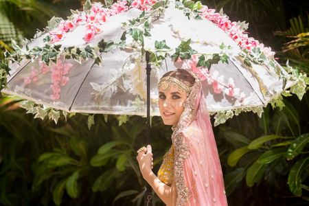 Photo of Bride entering under floral umbrella with pink and greens
