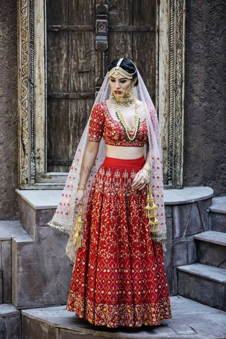 Photo of A bride in red poses on her wedding day