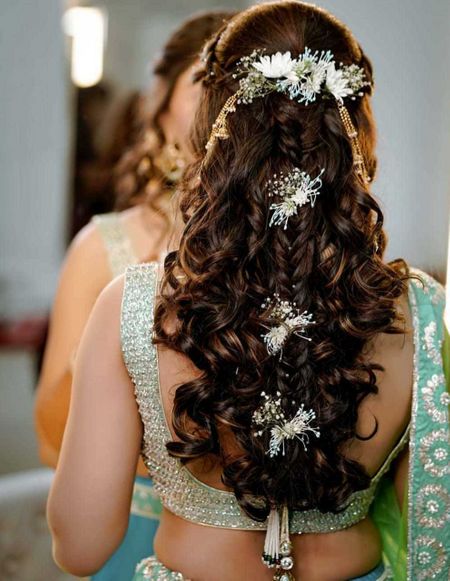 Half tied hairdo with soft curls, some braids, and flowers.
