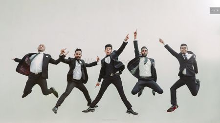 Groom jumping with groomsmen