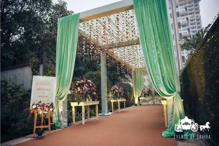 Photo of Simple yet elegant entrance decor for a outdoor event in green velvet drapes and hanging florals