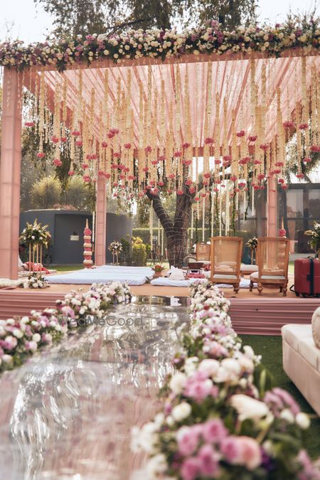 Photo of Pretty white and pink hanging florals mandap for an outdoor wedding with a mirror aisle