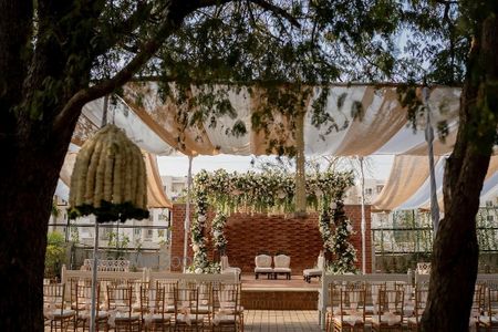 Lovely outdoor mandap with white florals and foliage for a day wedding