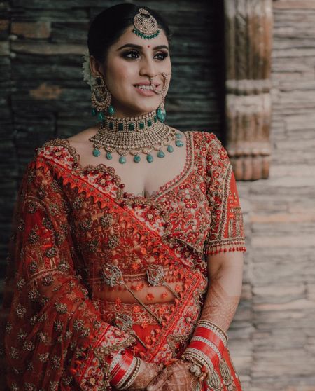 Photo of Bride wearing a red lehenga and posing on her wedding day.