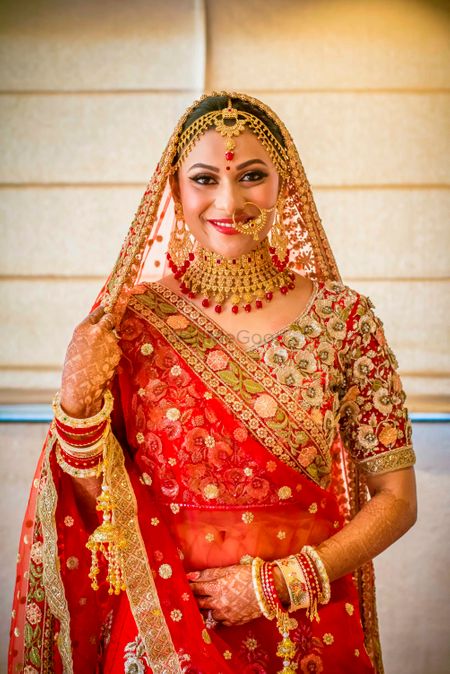 Bride in red lehenga and gold jewellery

