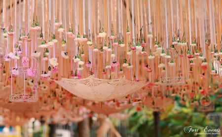 Beautiful peach decor with suspended umbrella and bird cage for mehendi