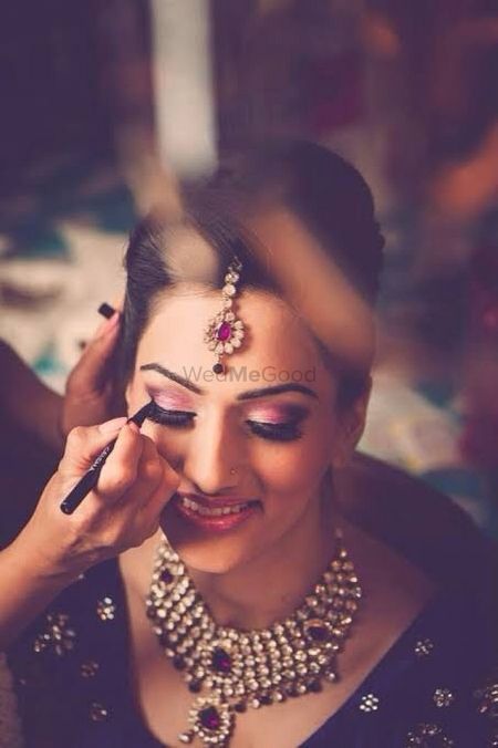 Photo of MUA putting eyeliner on bride