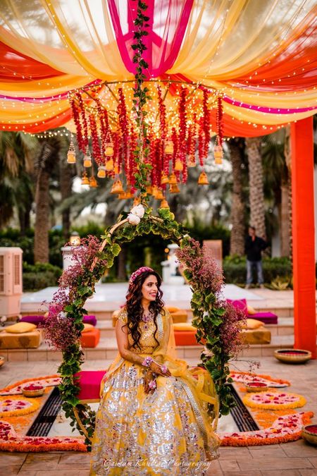Bridal mehendi seat decor idea with bride in yellow lehenga 