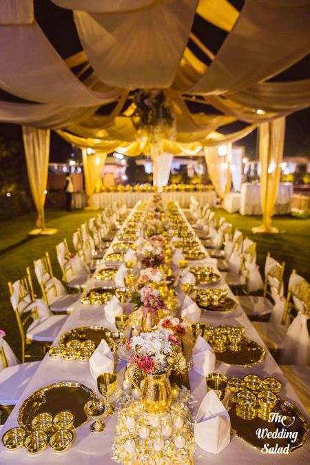 Photo of gold jugs with flower arrangements in table setting