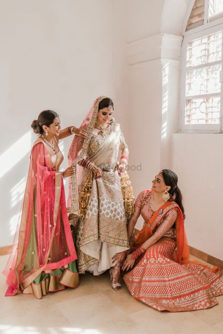 Bride in ivory with sisters helping her