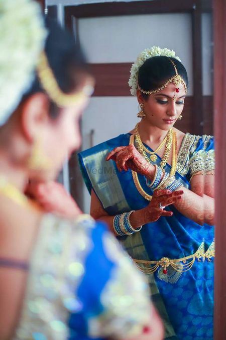 Photo of Bride looking into mirror wearing blue silk saree