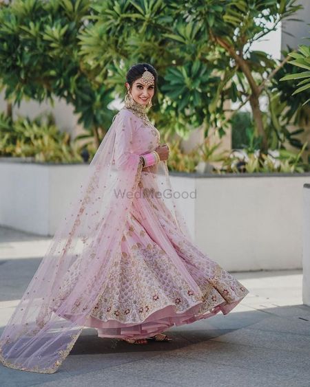 Twirling shot of a bride dressed in light pink lehenga