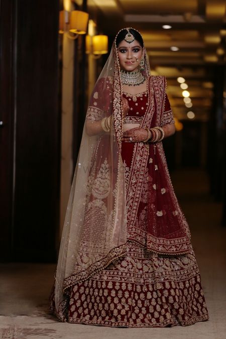 A beautiful bride in a stunning dark red lehenga and subtle makeup. 