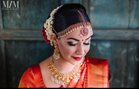 Photo of South Indian bride wearing smokey eyes and red lips.