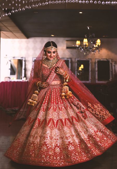 Photo of bride twirling in a red lehenga