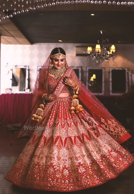 Photo of bride twirling in a red lehenga