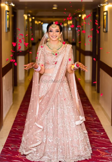 Happy bride in pastel pink lehenga and petals 