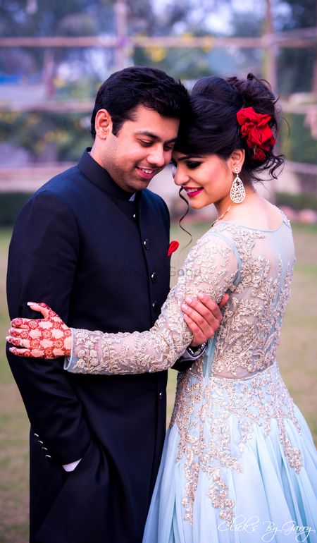 Engagement look with sheer pale blue gown and red roses in hair