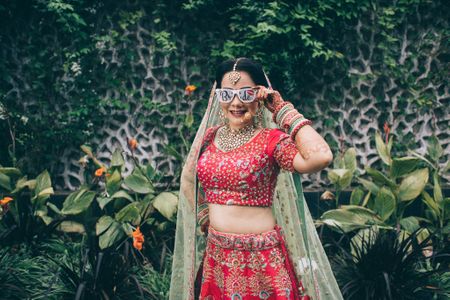 Bride wearing a sunglasses with a pretty red bridal lehenga 