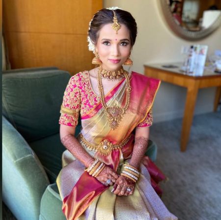 South Indian bride in a pink and dull gold saree.