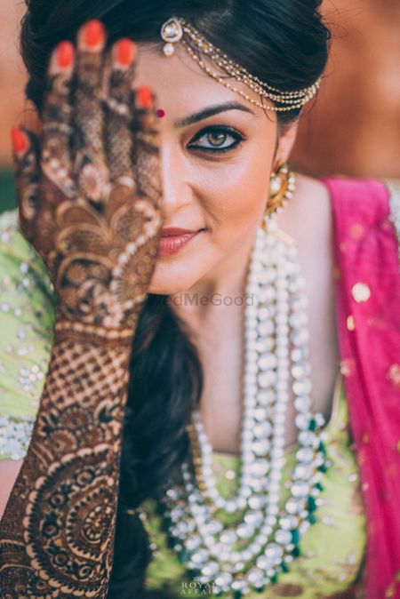 Bride showing off mehendi on hand covering face