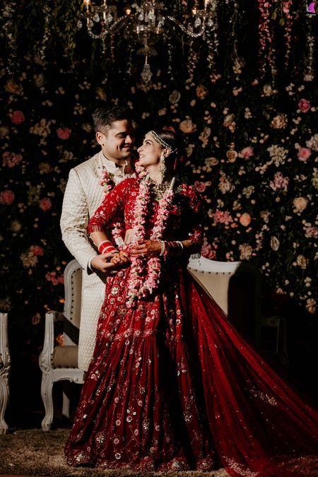 couple portrait in floral lehenga and against floral backdrop