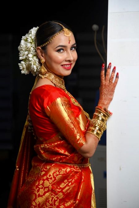 A bride in an orange banarasee saree with gajra in her hair