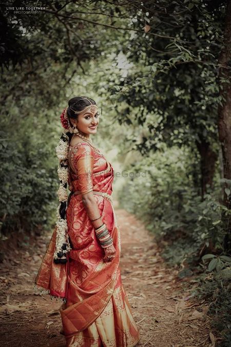 A south Indian bride in a red kanjeevaram with gajra in her hair 