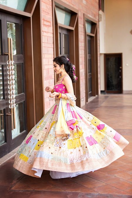 Bride twirling around in her multi-coloured lehenga.