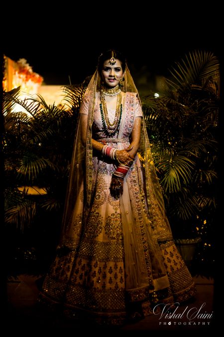 light pink bridal lehenga with contrasting green jewellery and waistbelt