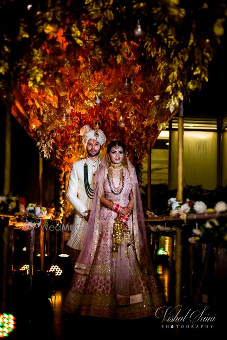 Photo of bride and groom against backdrop in pastel outfits