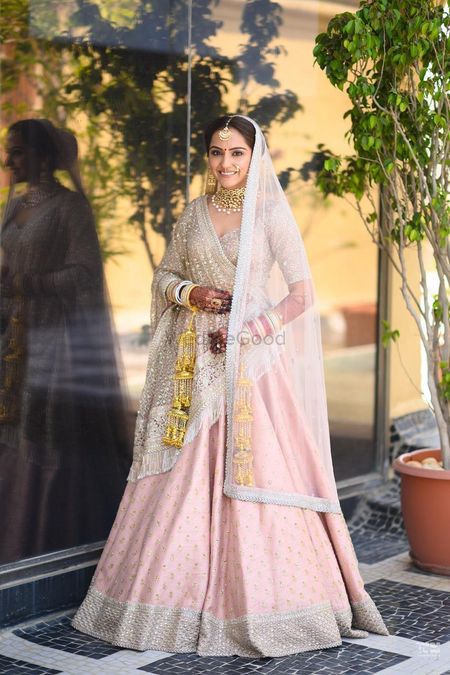 Photo of A bride in a blush pink lehenga with golden kalire