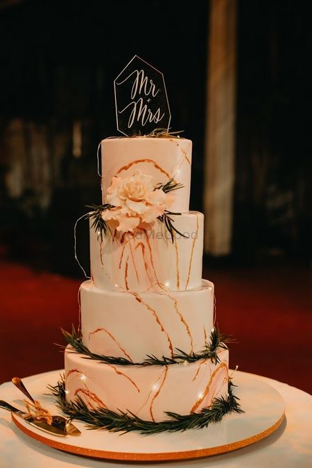 Photo of elegant white and peach wedding cake with topper