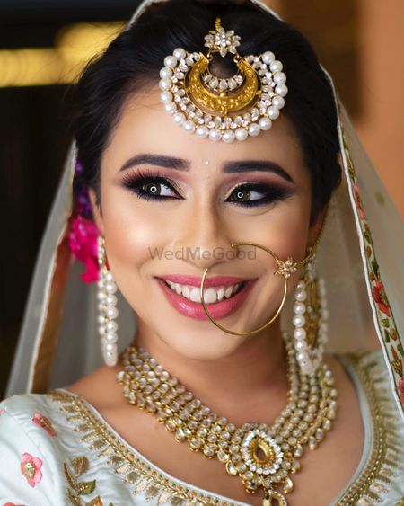 A happy bride in subtle makeup and gold jewellery. 