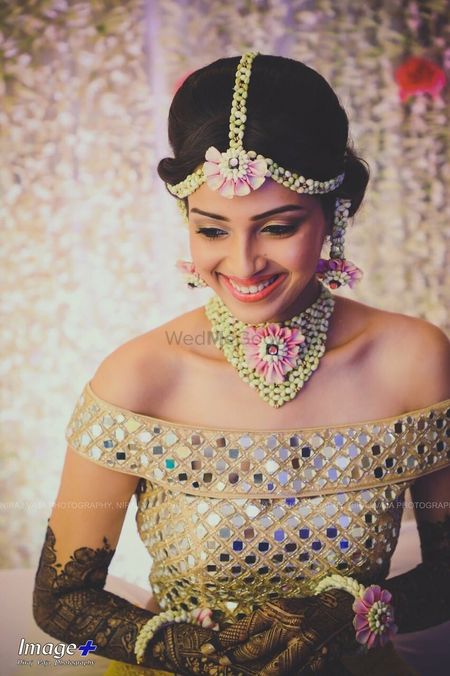 A to-be-bride in an off-shoulder top and floral jewellery on her mehndi ceremony