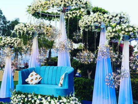 Alluring sangeet decor idea with flowers, curtains and lights. 