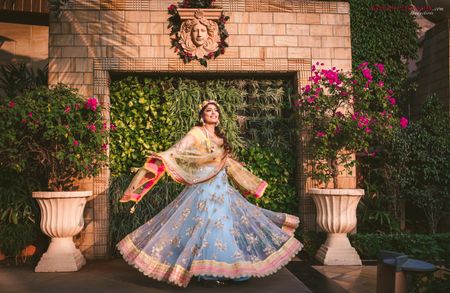 Photo of A bride in a blue net lehenga twirling on her mehndi day