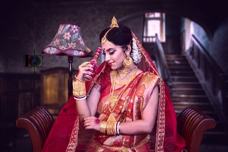 Photo of Bengali bride in red saree and gold jewellery.