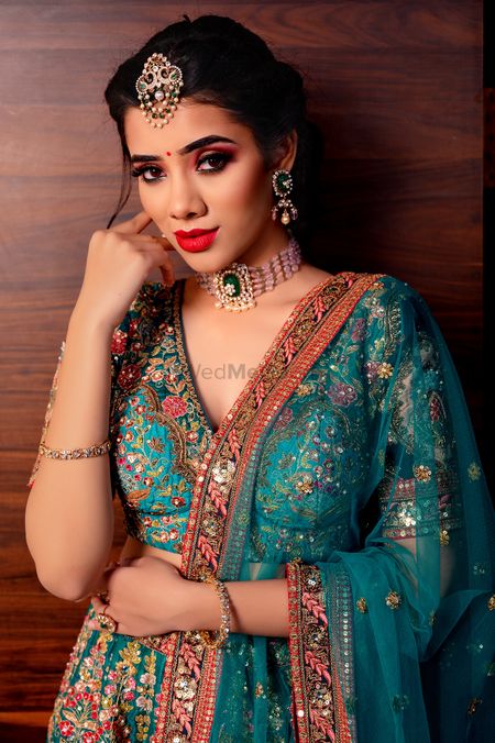 Bride in off-beat jewelry and blue embroidered lehenga. 