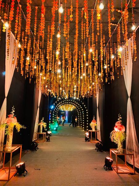 Entrance walkway decorated with sequinned strings, bulbs and floral vases.
