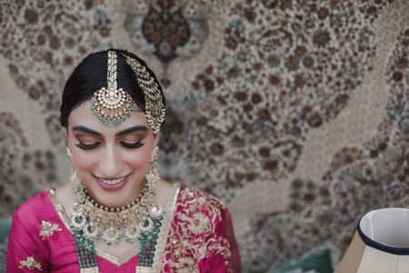 Bride wearing pink outfit with contrasting jewellery in green.