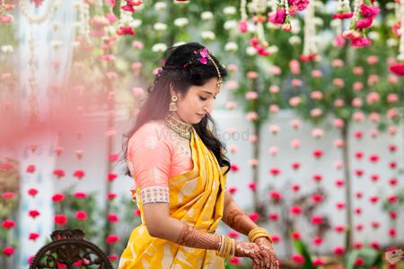A bride in a yellow and peach silk saree