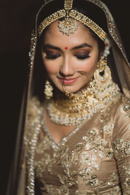 Close up shot of a bride in gold lehenga.