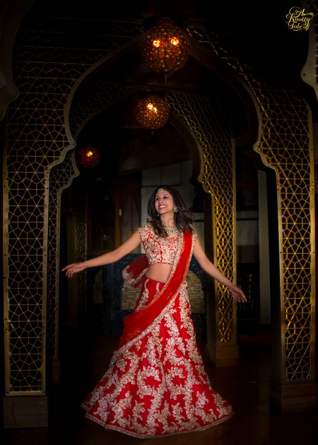 Photo of twirling bride in red and gold lehenga