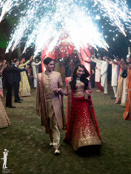 Photo of Outdoor wedding idea for bride and groom entry with guests holding cold pyros