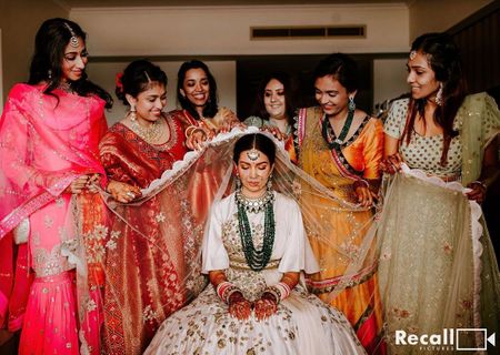 Photo of bride with her bridesmaids placing dupatta on her head