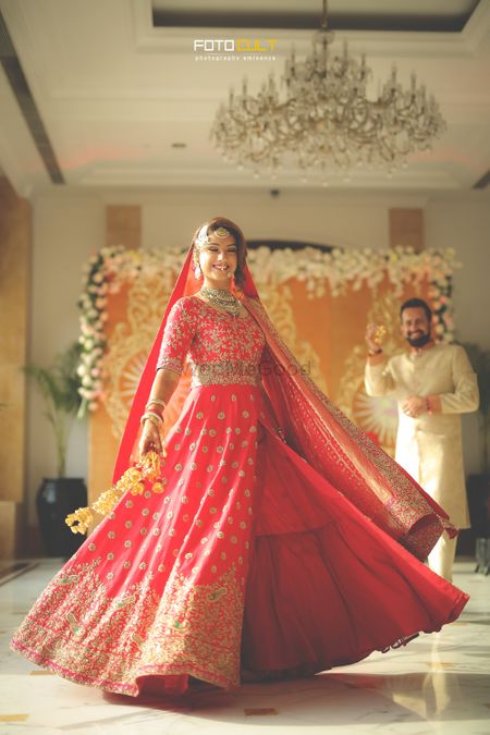 Bride twirling in red layered Anarkali lehenga