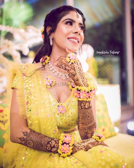 Photo of Bride in yellow mehendi lehenga and floral jewellery