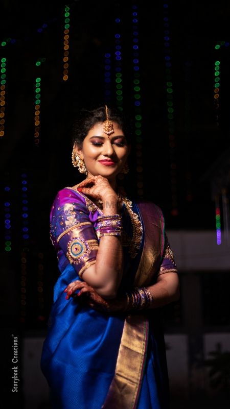 South Indian bride wearing a royal blue saree with a purple blouse.