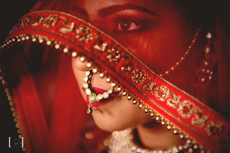 Photo of Bride in veil shot in red dupatta and nath